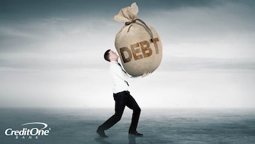 A young businessman struggles to carry a large burlap bag with the word “Debt” on it, representing the large burden of carrying debt like the average person.