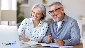 A senior couple smiles as they review their finances on a laptop, perhaps happy that jumbo CDs have proven to be a good investment.