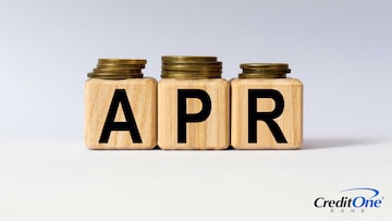 Stacks of coins in various heights sit on top of three wooden blocks spelling out APR, which represents how a credit card APR may get higher based on various criteria.